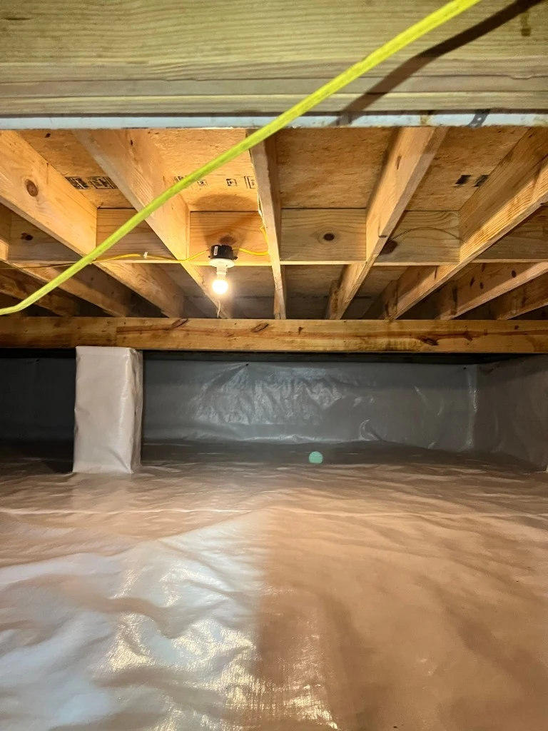 Clean encapsulated crawlspace with white vapor barrier and illuminated framing in Somerset KY
